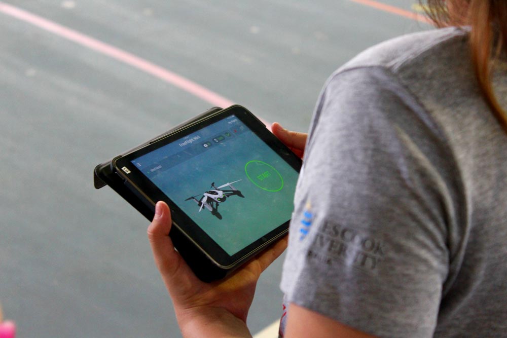 an over the shoulder view of a girl operating a drone flight app on her iPad